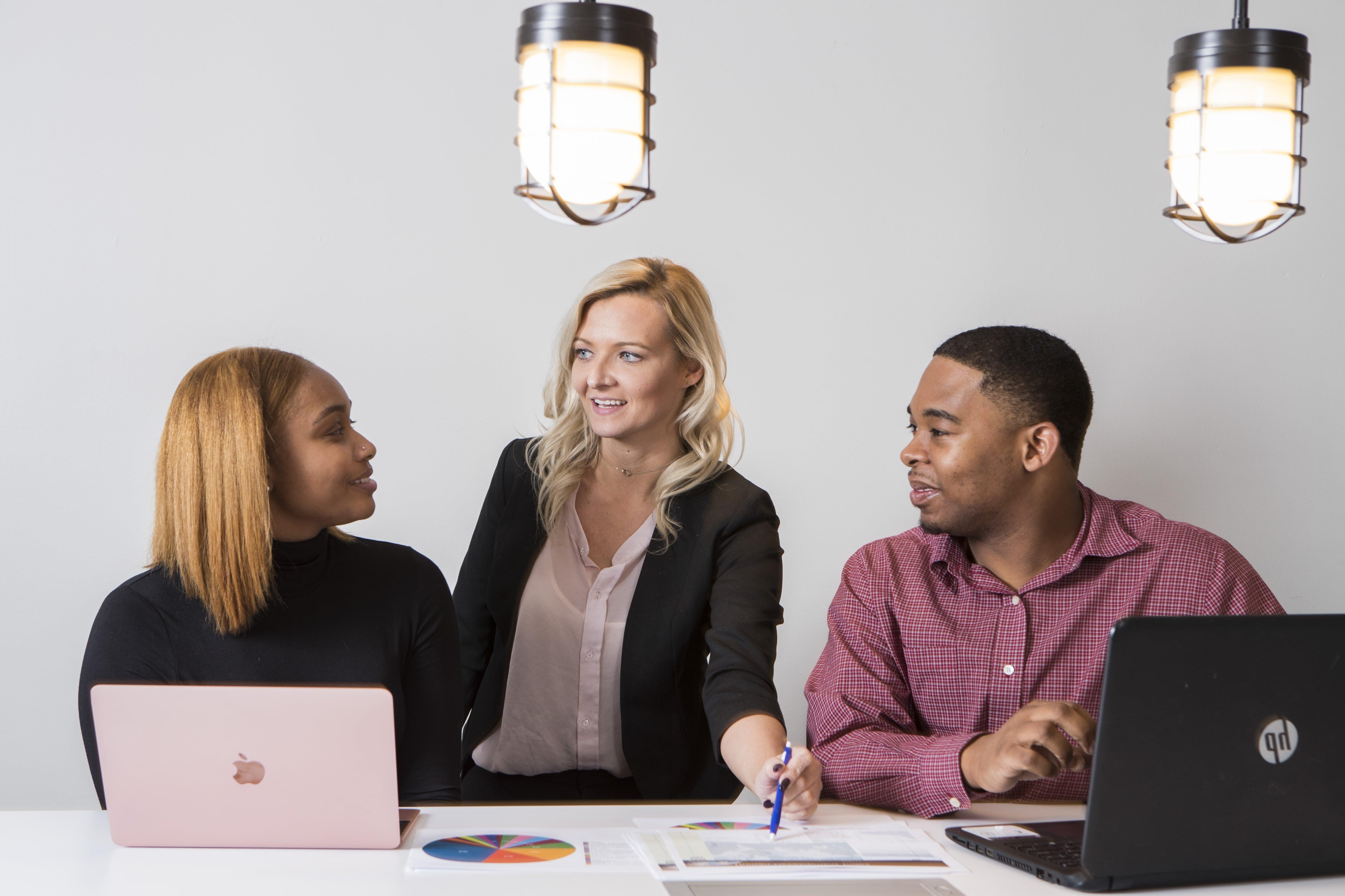 Three colleagues communicating at a table.